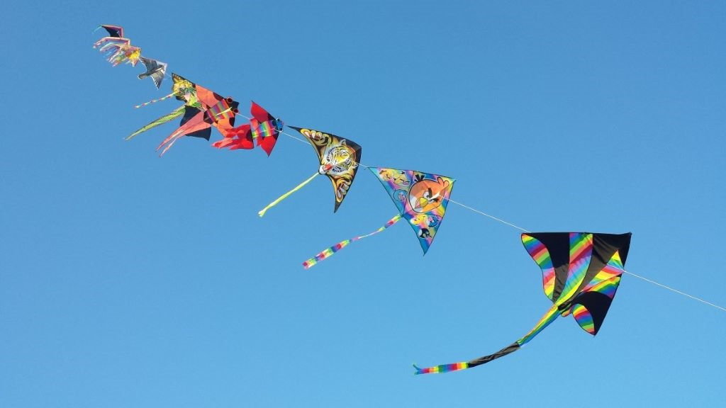 Unha ringleira de papaventos unidos voando no ceo azul (Foto: Pxhere).