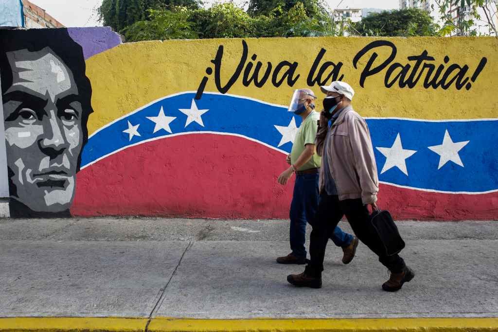 Dous homes pasan en Caracas por diante dun mural chavista. (Foto: DPA-Europa Press)
