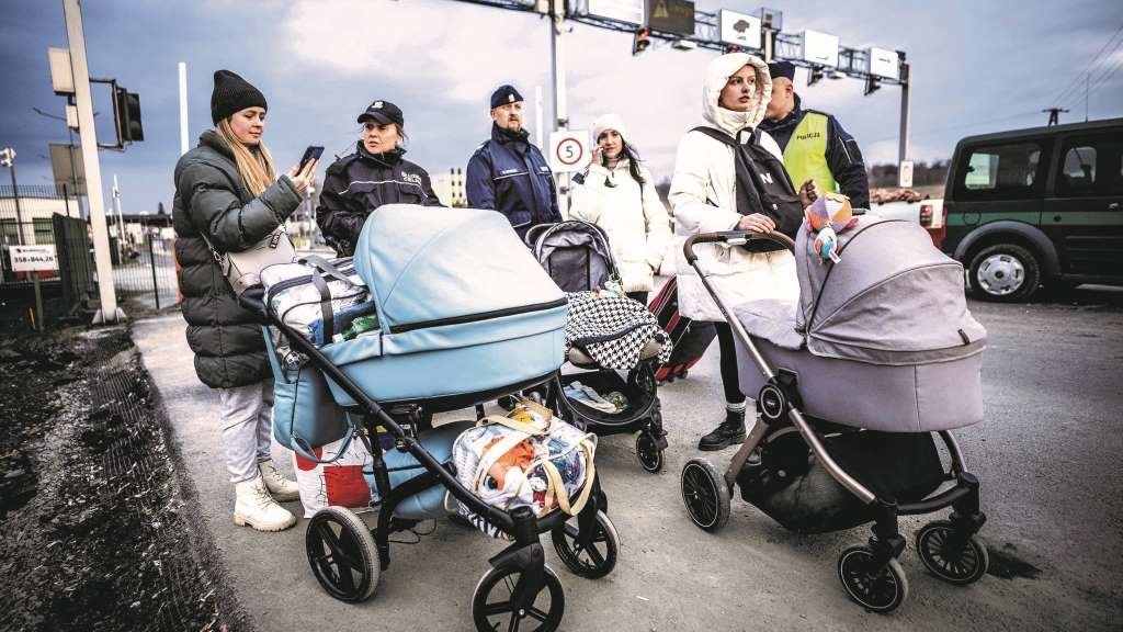 Tres refuxiadas ucraínas son guiadas por policías tras cruzar a fronteira con Polonia cos seus bebés (Foto: Michael Kappeler / dpa).