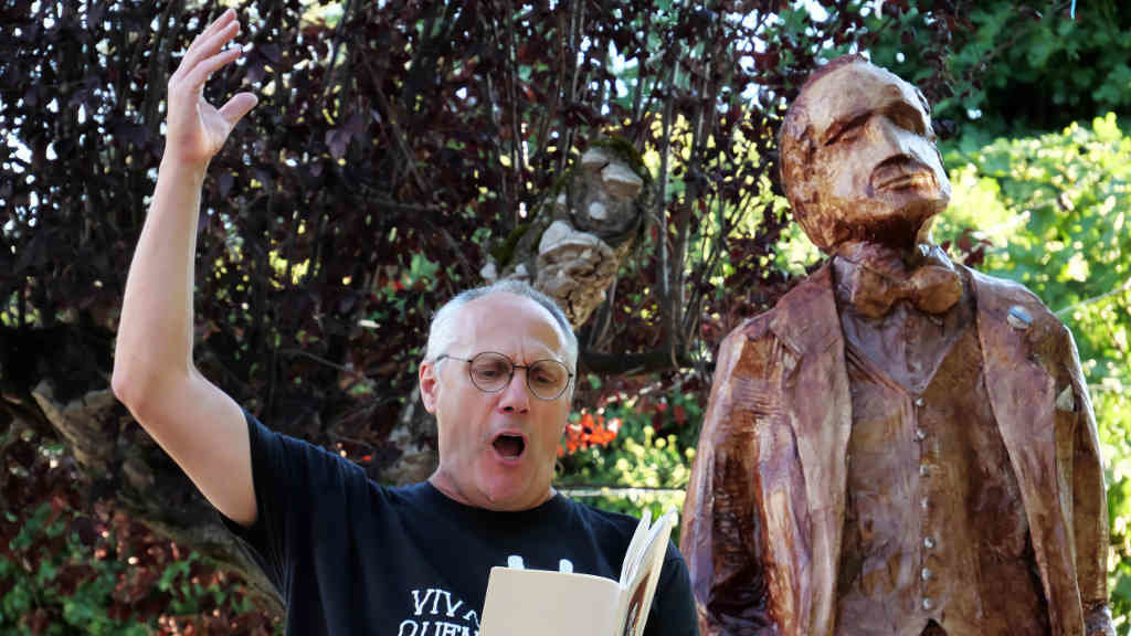 O activista e artista Anxo Baranga lendo textos de Delgado Gurriarán ao carón da súa escultura en Córgomo. (Foto: Nós Diario).