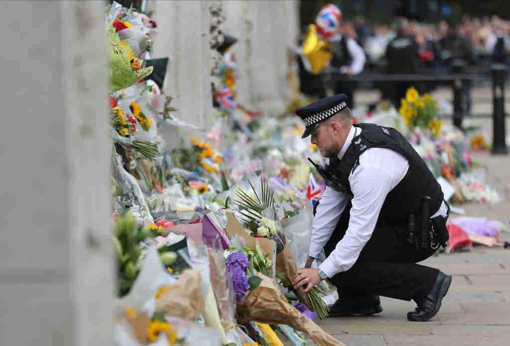 Un policía coloca flores á porta do palacio de Buckingham (Londres). (Foto: Elisa Bermudez / Europa Press)