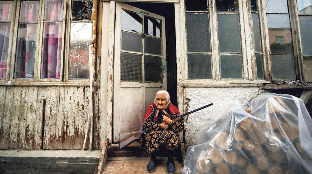 Unha muller armenia suxeita unha escopeta na entrada da súa casa durante un bombardeo das tropas de Acerbaixán (Foto: Celestino Arce Lavin / ZUMA Wire / DPA).