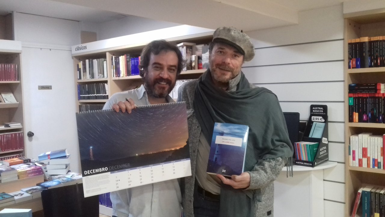O escritor Pedro Feijoo, sostendo o calendario Ceos Galegos, e X. Dosi Veiga, con &#39;Un lume azul&#39;, ambos coa foto do mesmo faro.