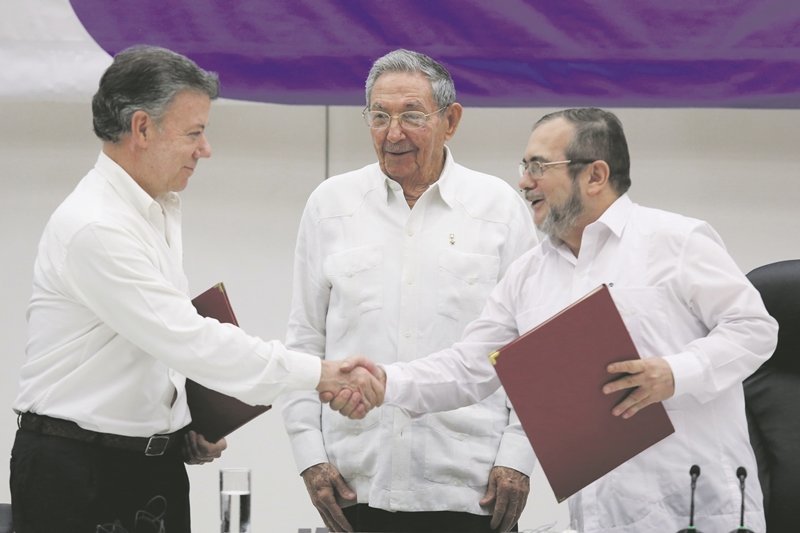 Cuba's President Raul Castro (C) looks as Colombia's President Juan Manuel Santos (L) shakes hands with FARC rebel leader Rodrigo Londono, better known by his nom de guerre Timochenko, after signing a historic ceasefire deal between the Colombian government and FARC rebels in Havana, Cuba, June 23, 2016. REUTERS/Alexandre Meneghini      TPX IMAGES OF THE DAY     
