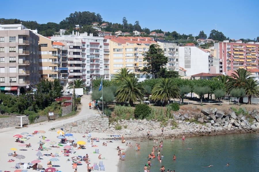 Ba&ntilde;istas na praia de Silgar, coa vila de Sanxenxo ao fondo (Imaxe: Wikimedia).