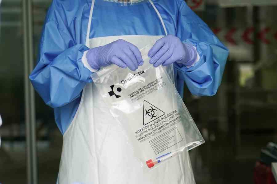 Un sanitario protegido con guantes sostiene una bolsa en la que hay una muestra para realizar un Análisis PCR e