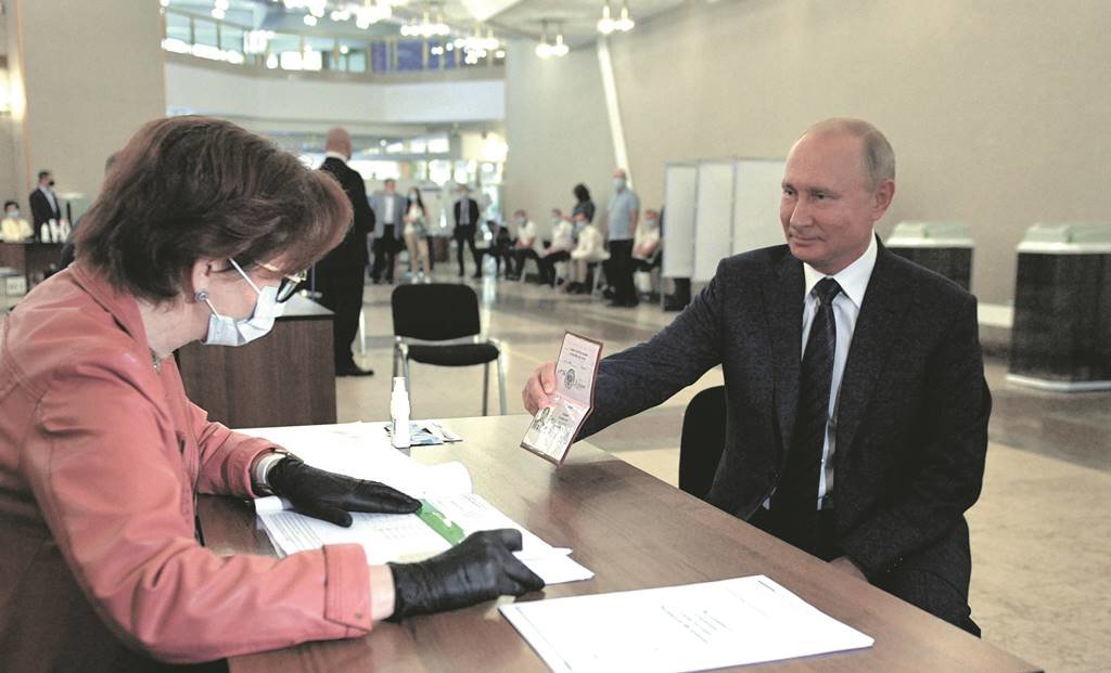 epa08519807 Russian President Vladimir Putin (R) shows his passport while taking part in a nationwide vote on amendments to the Russian Constitution during the main day of vote at a polling station in Moscow, Russia, 01 July 2020. The polling stations were opened for vote on 25 June to avoid crowding amid ongoing COVID-19 disease in Russia.  EPA/ALEXEI DRUZHININ / SPUTNIK / KREMLIN POOL MANDATORY CREDIT ORG XMIT: FET23