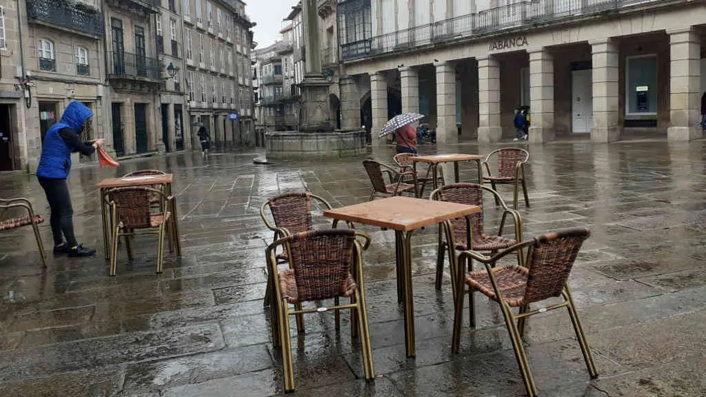 Traballador da hostalar&iacute;a preparando unha das mesas nunha terraza en Compostela (Foto: Riob&oacute; Prada)