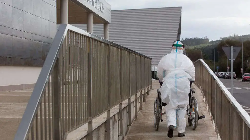 Un sanitario, cunha cadeira de rodas, xunto a unha residencia. (Foto: Carlos Castro / Europa Press)