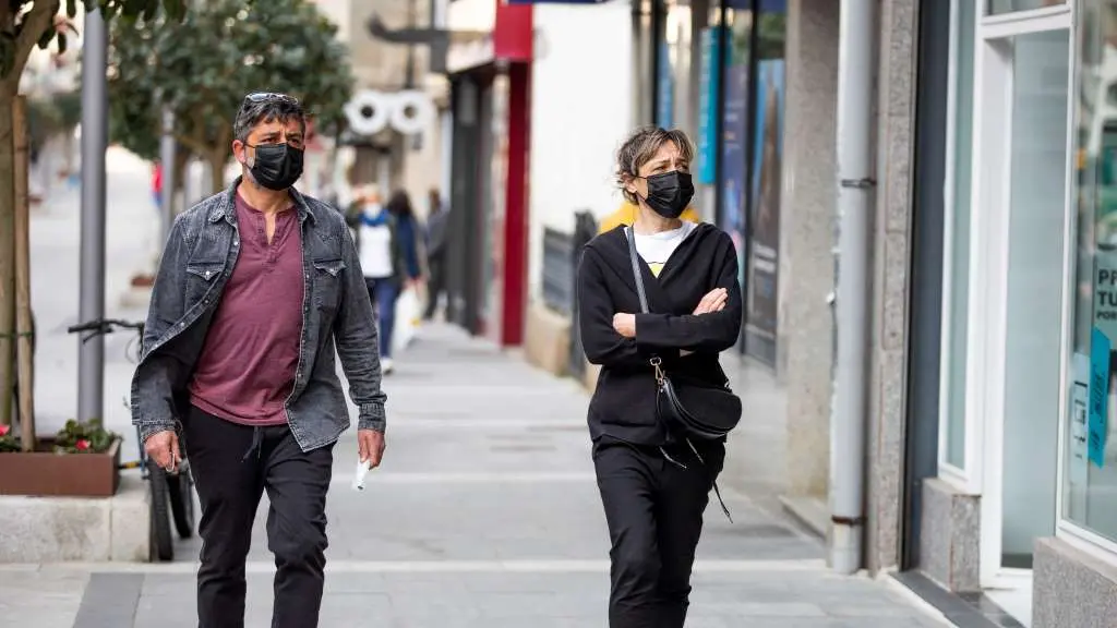 Un home e unha muller cami&ntilde;an por unha r&uacute;a do Grove, que fica no nivel m&aacute;ximo de restrici&oacute;ns (Foto: Beatriz Ciscar / Europa Press).
