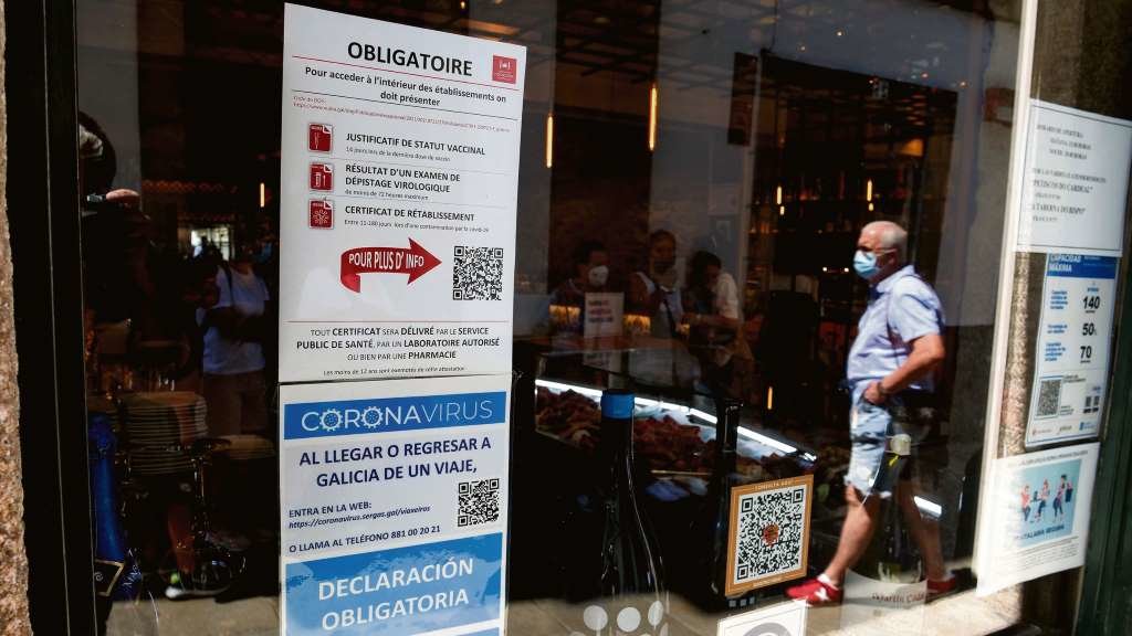Cartaces en diferentes idiomas advertindo da obrigatoriedade do certificado, nun local da rúa do Franco de Compostela (Foto: Arxina).