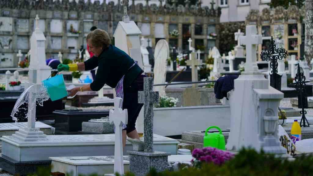 Unha muller limpa unha lápida no cemiterio de Quintana dos Mortos de Santa María A Nova, en Noia (Foto: Álvaro Ballesteros / Europa Press)