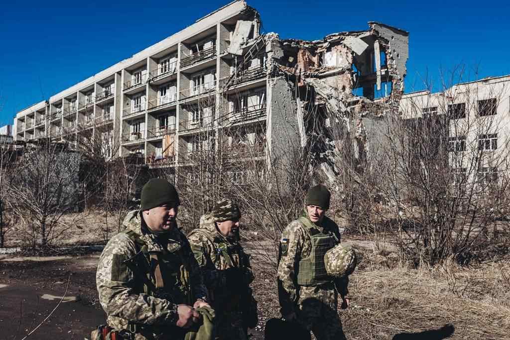 EuropaPress_4255397_varios_soldados_ucranianos_caminan_frente_edificio_derruido_pueblo_cercano