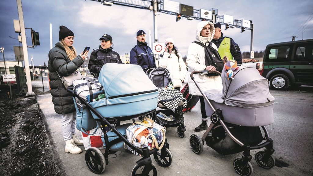 Tres refuxiadas ucraínas son guiadas por policías tras cruzar a fronteira con Polonia cos seus bebés (Foto: Michael Kappeler / dpa).