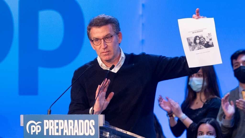 Alberto Núñez Feixoo sostén un cartaz cos rostros de Martínez-Almeida e Díaz Ayuso, un "tándem electoral infalíbel", dixo (Foto: Alberto Ortega / Europa Press).