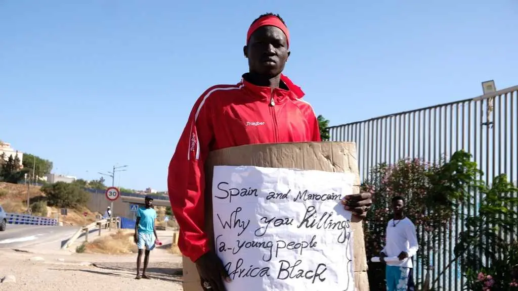 Un home sost&eacute;n un cartel no que se pode ler "Espa&ntilde;a e Marrocos, por que matan xente negra e moza de &Aacute;frica?". (Foto: Antonio Ruiz / Europa Press)