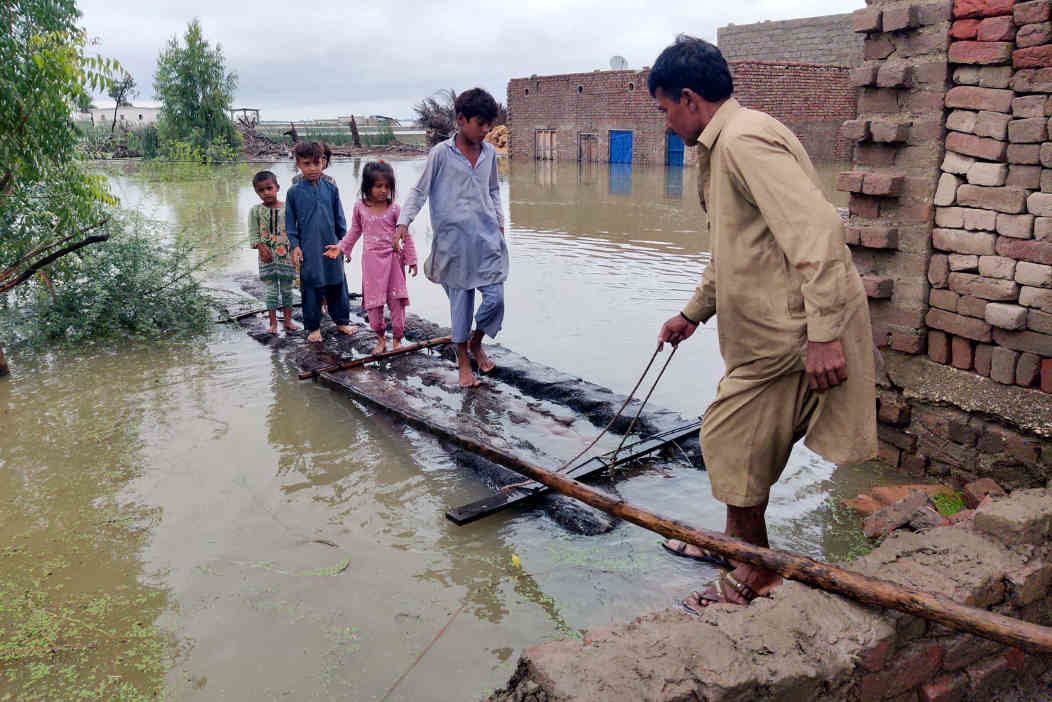 Un home axuda os nenos a cruzar polas zonas inundadas. (Foto: PPI via ZUMA Press Wire / dpa)