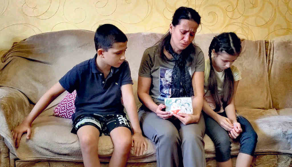 Tonya, com os dois filhos, mostra a foto da pequena Masha, falecida en Gorlovka, Donetsk. (Foto: Bruno Carvalho)