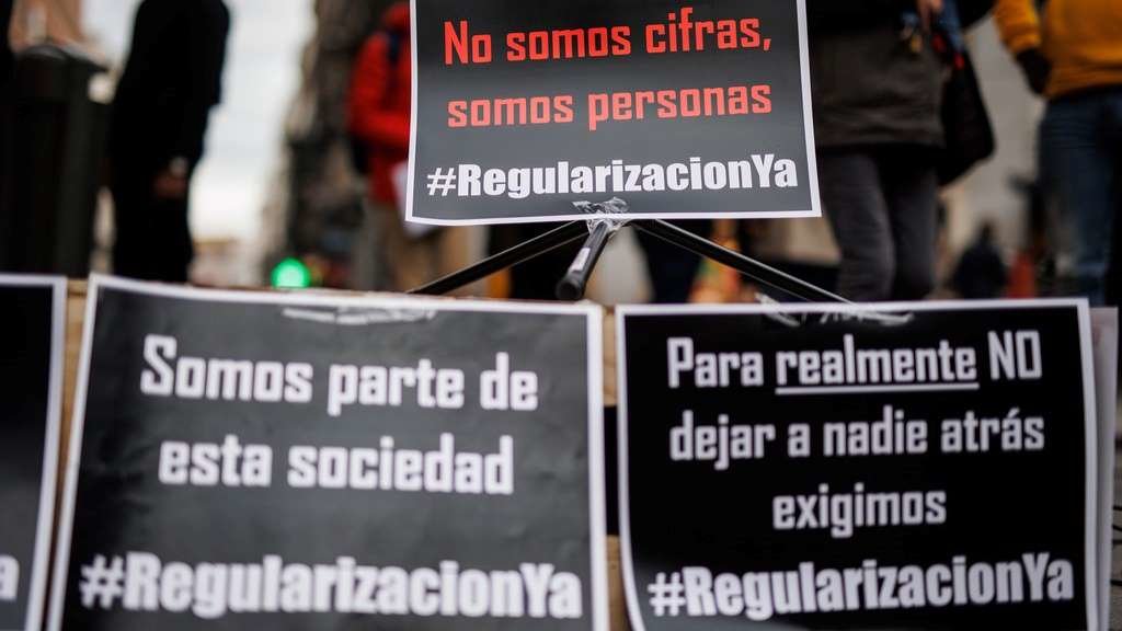 Cartaces a prol da regularización nun acto de recollida de sinaturas para a ILP. (Foto: Alejandro Martínez Vélez / Europa Press)