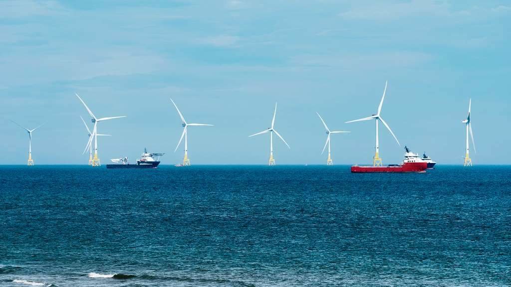 Aeroxeradores dun parque eólico mariño fronte á costa de Aberdeen, en Escocia, con barcos pesqueiros navegando ao seu carón. (Foto: Federico Rostagno)