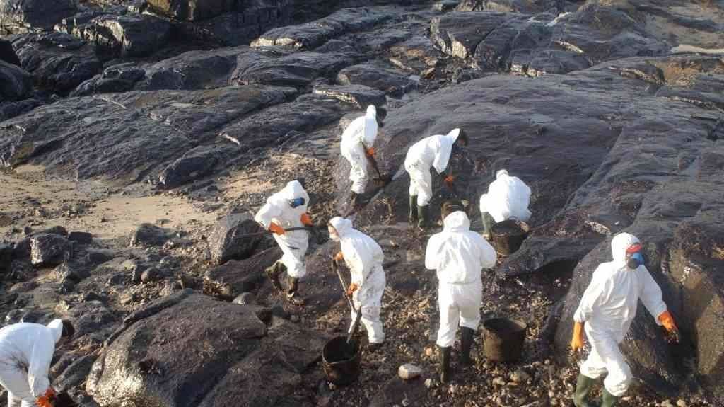 Persoas voluntarias recollendo chapapote dunha praia após a catástrofe do 'Prestige'. (Foto: Europa Press)