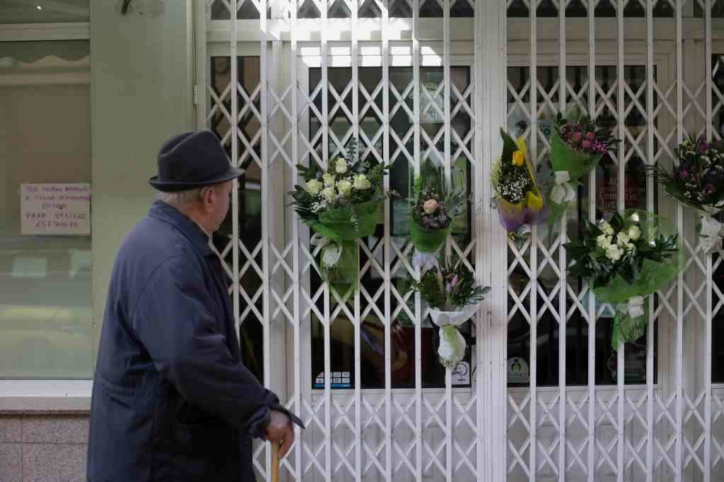 Un home vendo as flores que lembran a asasinada no valado da tenda en que traballaba. (Imaxe: Carlos Castro / Europa Press)