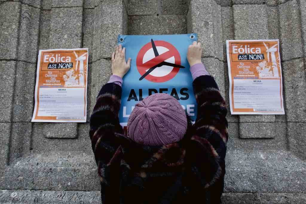 Unha muller pega un cartaz contra a invasión eólica en Meira, o 11 de decembro. (Foto: Europa Press)