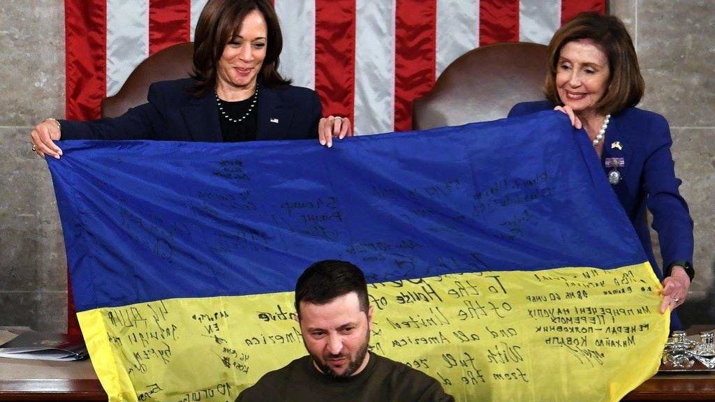 O presidente ucraíno, Volodimir Zelenski, arroupado por unha bandeira do seu país sustentada pola vicepresidenta dos EUA, Kamala Harris, e a líder do Congreso, Nancy Pelosi. (Foto: Carol Guzy / ZUMA Press Wire)
