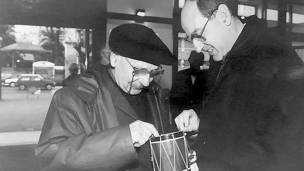 Manuel Monge (dereita) xunto ao pintor vasco Agust&iacute;n Ibarrola (esquerda), na Coru&ntilde;a, en 2005.Na imaxe est&aacute; buscando a s&uacute;a firma no tambor que regalaba a comuna aos presos cando saian do c&aacute;rcere, xa que ambos os dous coincidiron no de Basauri.