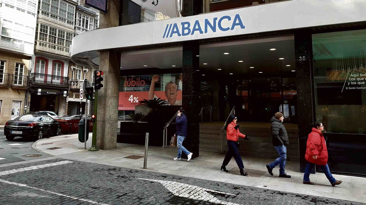 Varias persoas camiñan por diante da sede de Abanca na cidade da Coruña. (Foto: Nós Diario)