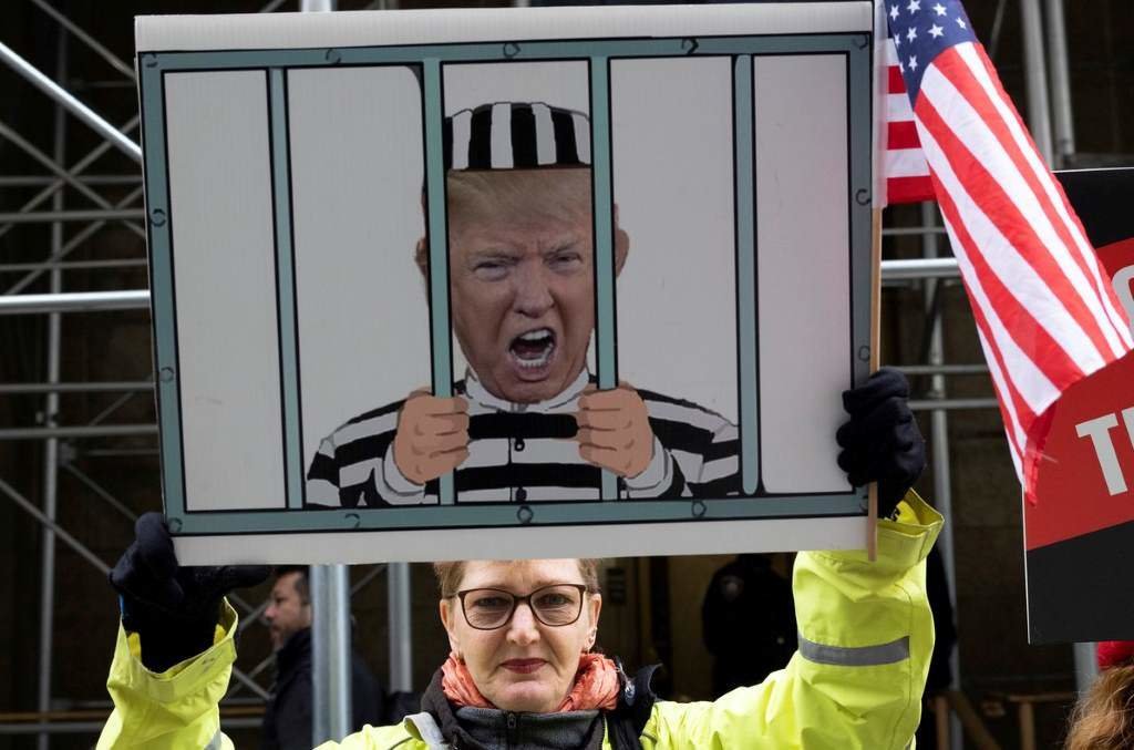 Unha muller sostén un cartaz con Donald Trump apresado. (Foto: Gina M. Randazzo)