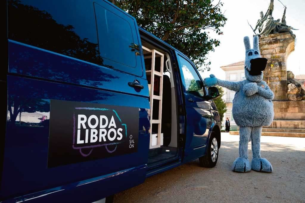 Orbil, a mascota do Salón, invitando a entrar na 'Rodalibros' a furgoneta biblioteca que levará actividades polas parroquias.