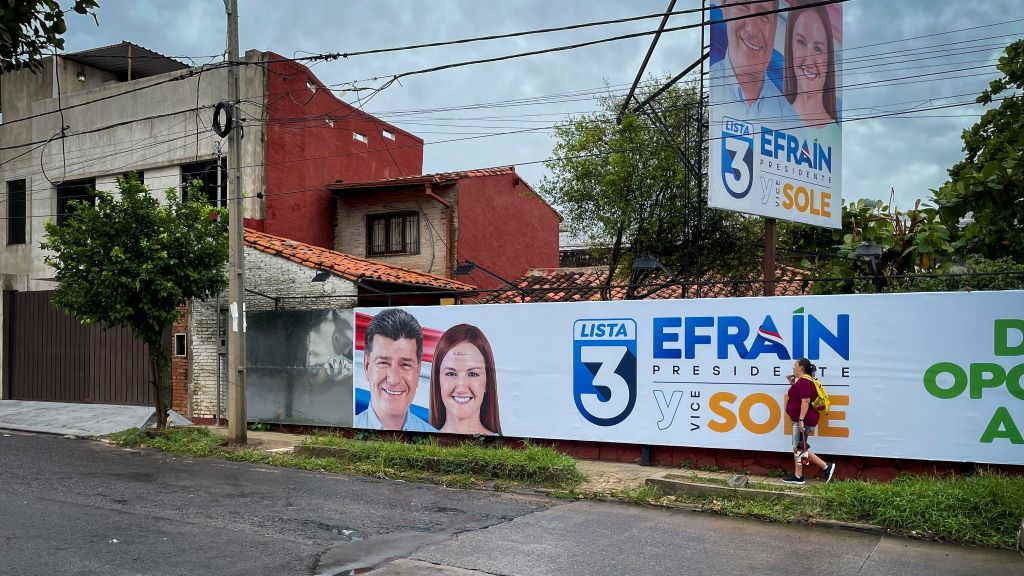 Unha muller camiña ante unha pancarta electoral do candidato presidencial de Paraguai Efraín Alegre. (Foto: Andre M. Chang).