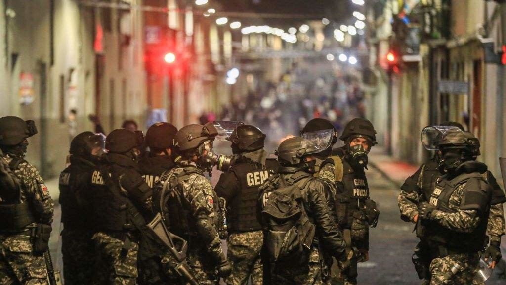 Policías ecuatorianos ante un gran grupo de persoas nunha protesta contra o Goberno Lasso, o pasado ano. (Foto: Juan Diego Montenegro / Europa Press / Contacto)