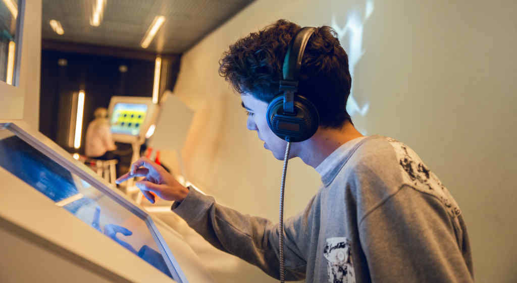Un mozo nunha pantalla táctil dun museo (Foto: Nós Diario).
