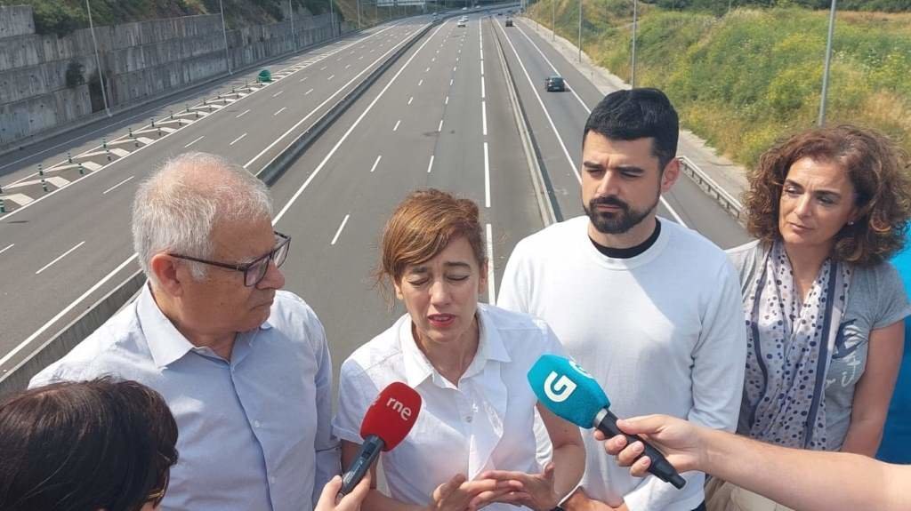 Marta Lois compareceu ante os medios, na compaña doutros integrantes da lista de Sumar na Coruña, desde unha ponte que cruza a autoestrada por Santiago. (Foto: Europa Press)