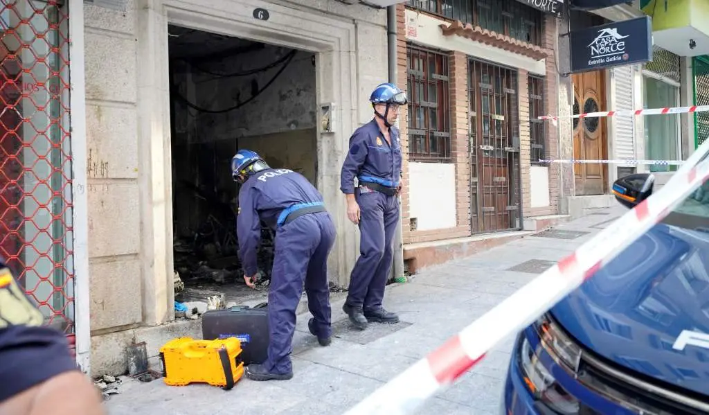 Dous axentes de polic&iacute;a traballando no portal n&uacute;mero 6 da r&uacute;a Alfonso X o Sabio de Vigo, onde se produciu o tr&aacute;xico incendio que acabou coa morte de catro persoas. (Foto: Javier V&aacute;zquez / Europa Press)