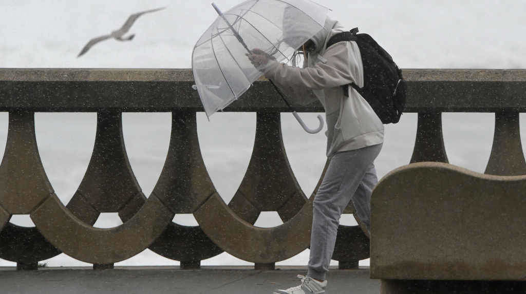 Unha persoa protéxese da chuvia e do vento durante un temporal na Coruña (Foto: M. Dylan / Europa Press).