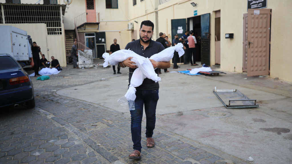 Un voluntario leva os corpos sen vida de dúas crianzas palestinas após un ataque israelí (Foto: Ahmed Ibrahim / Zuma Press / Contactophoto ).