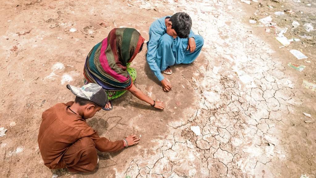 Tres crianzas xogan nas terras secas do que antes foi unha zona inundada na aldea de Geokaloi, en Sindh, no sur de Paquistán. (Foto: Vlad Sokhin  / Unicef)