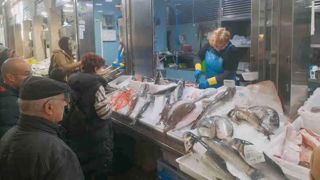 Clientes mercando peixe nun posto da praza de Abastos de Santiago de Compostela (Foto: Riob&oacute; Prada).