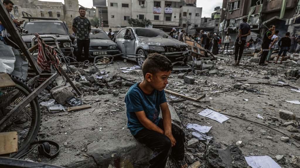 Un neno palestino sentado entre os cascallos dun edificio destruído, tras un ataque aéreo israelí no sur de Gaza (Foto: Abed Rahim Khatib).