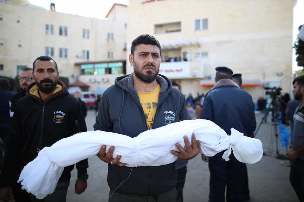 Un palestino carga unha crianza asasinada por Israel. (Foto: Europa Press / Contacto / Xinhua)