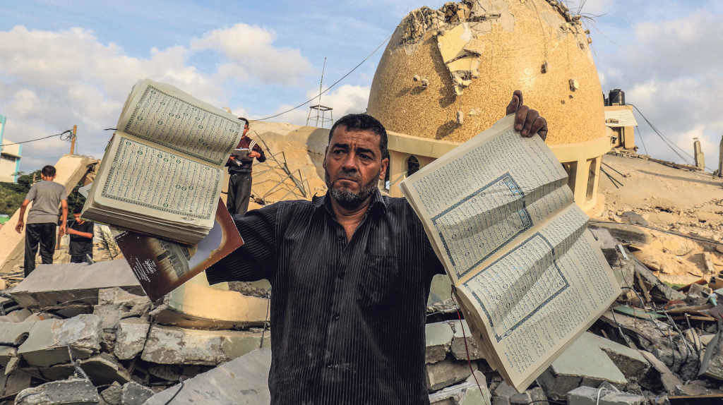 Un palestino sostén libros do Corán fronte a unha mesquita destruída por Israel na cidade de Khan Yunis, no sur de Gaza o 8 de outubro (Foto: Abed Rahim Khatib/dpa).