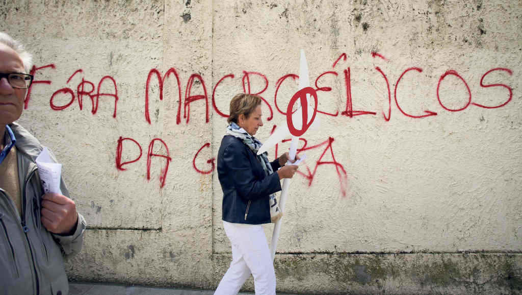 Unha muller pasando por diante dunha pintada durante a mobilización contra a burbulla eólica de maio de 2023 en Lugo
(Carlos Castro / Europa Press).