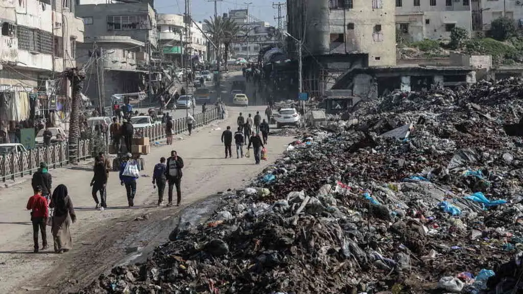 Os palestinos cami&ntilde;an xunto a unha morea de lixo na cidade de Gaza, no medio do alto o fogo entre Israel e Ham&aacute;s. (Foto: Omar Ashtawy/APA Images v&iacute;a ZUMA Press Wire/dpa)
