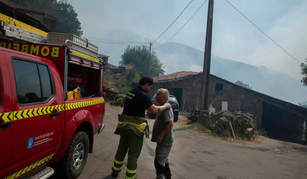 Manuel Fern&aacute;ndes Bah&iacute;a (delante) y un bombero en la aldea de Teixeira (Maceda) de spu&eacute;s de la noche con el fuego alrededor de la aldea.. FOTO Rosa Veiga. Ourense 10/08/25