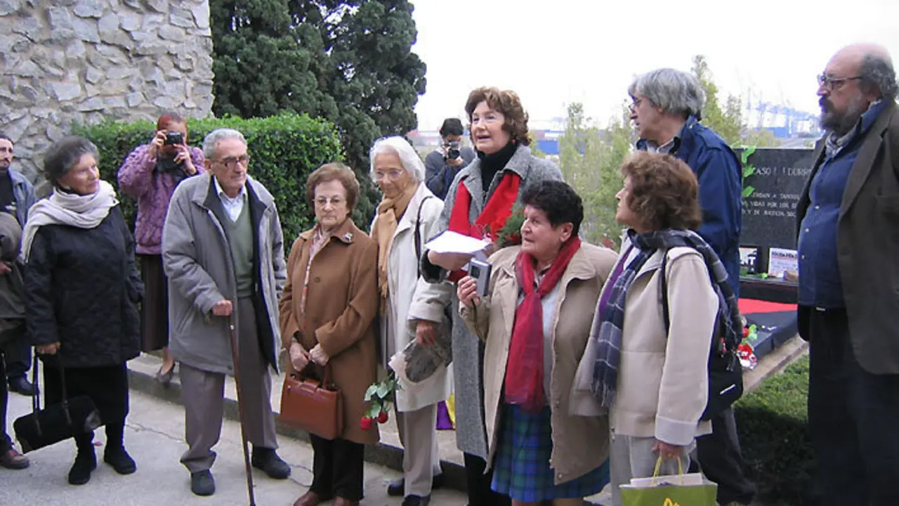 Joaquina Dorado, a suxeitar un bolso, entre Eduardo Pons e Colette Durruti, nunha homeanaxe a Buenaventura Durruti