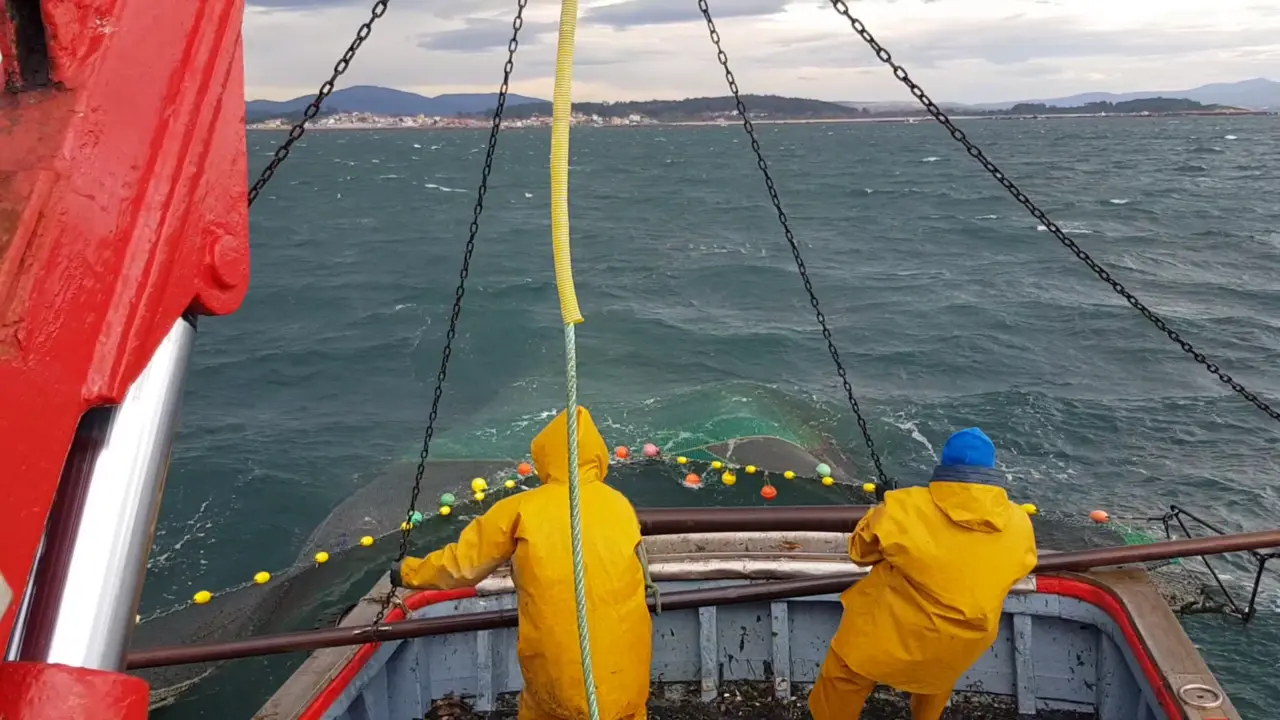 Dous mari&ntilde;eiros recollen redes de pesca de arrastre. (Foto: Os mares de baixura).