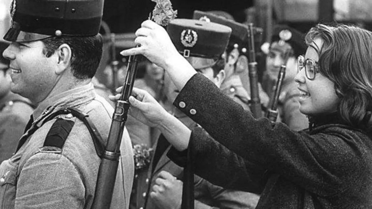 Celeste Caeiro coloca un caravel no fusil dun soldado. (Foto: Centro de Documenta&ccedil;&atilde;o 25 de Abril)